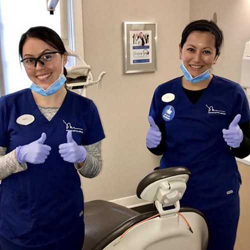 Two dental team members giving thumbs up in dental treatment room