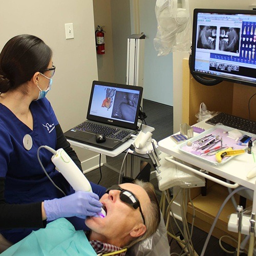 Dental team member using intraoral camera and reviewing x-rays