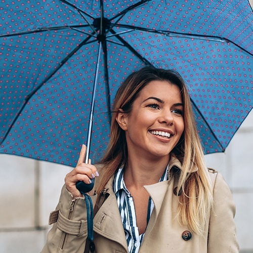 Woman smiling holding a blue umbrella