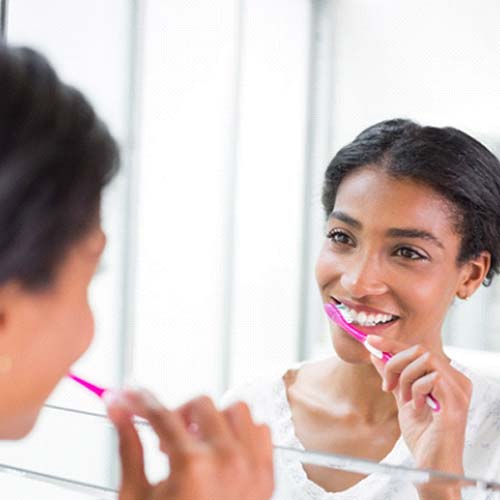 Woman brushing teeth to prevent dental emergencies in Willowbrook