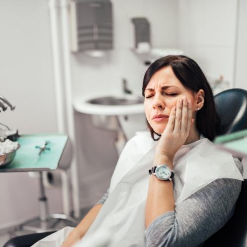 Woman holding cheek during emergency dentistry visit