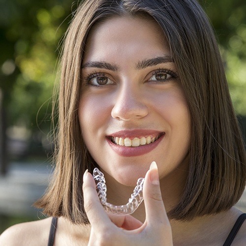 Woman holding an Invisalign clear braces tray