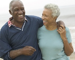 Senior couple on beach with implant dentures in Willowbrook, IL