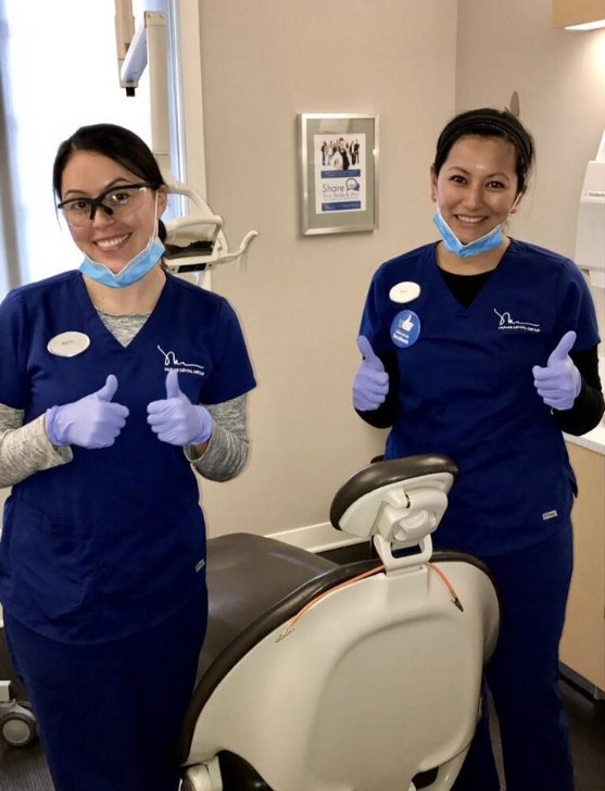 Two dental team members giving thumbs up in dentistry treatment room