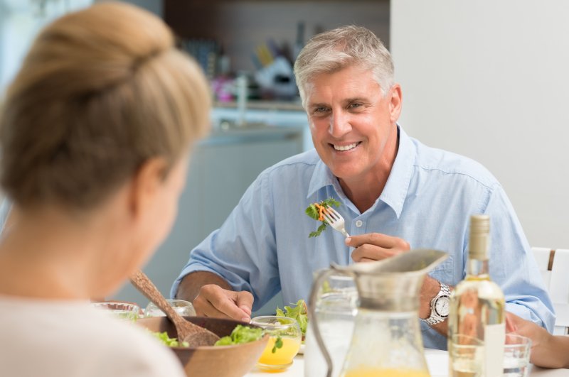 Man smiling while enjoying a meal with his wife